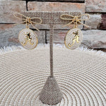 Gold bow earrings with pearl-accented medallion drops featuring the Alabama Script "A."