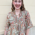 Brown, orange, and green printed smocked top with V-neck and tie neck