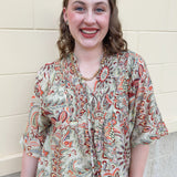 Brown, orange, and green printed smocked top with V-neck and tie neck