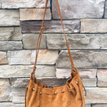 Camel faux suede slouchy shoulder bag with gold chain straps and drawstring-style closure.