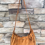 Camel faux suede slouchy shoulder bag with gold chain straps and drawstring-style closure.