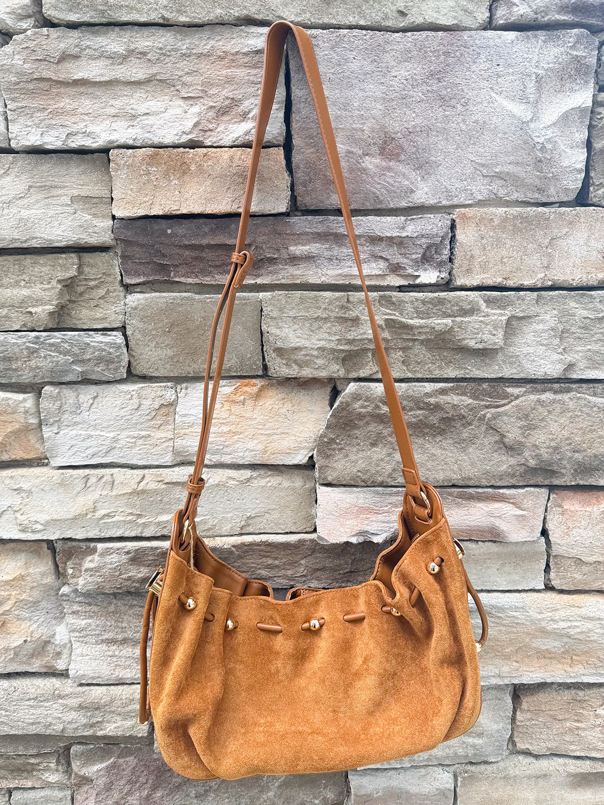Camel faux suede slouchy shoulder bag with gold chain straps and drawstring-style closure.