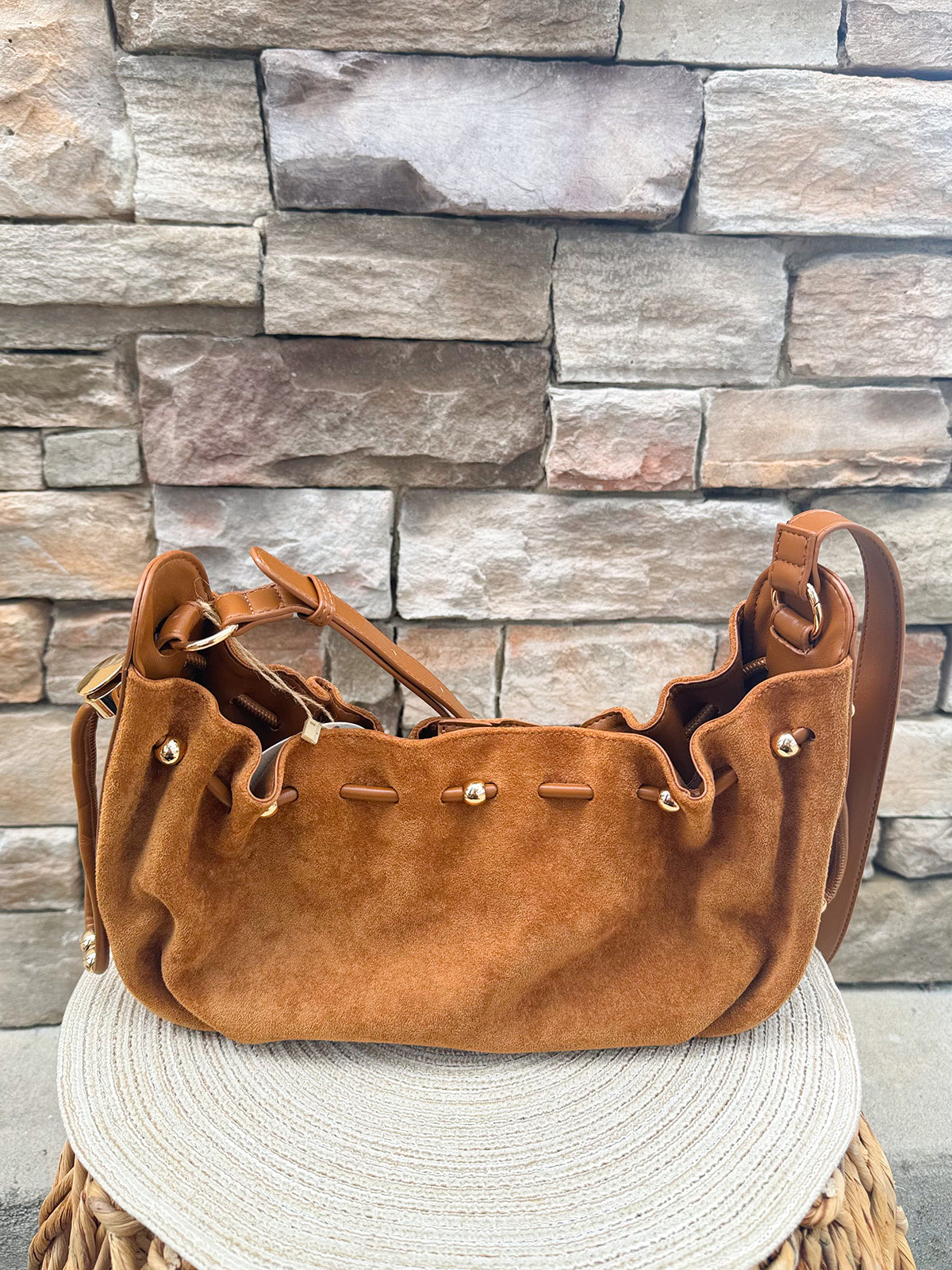 Camel faux suede slouchy shoulder bag with gold chain straps and drawstring-style closure.