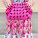 Hot pink woven handbag with a braided texture and knotted strap detail, offering a vibrant and chic everyday style.