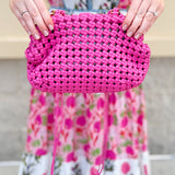 Hot pink woven handbag with a braided texture and knotted strap detail, offering a vibrant and chic everyday style.