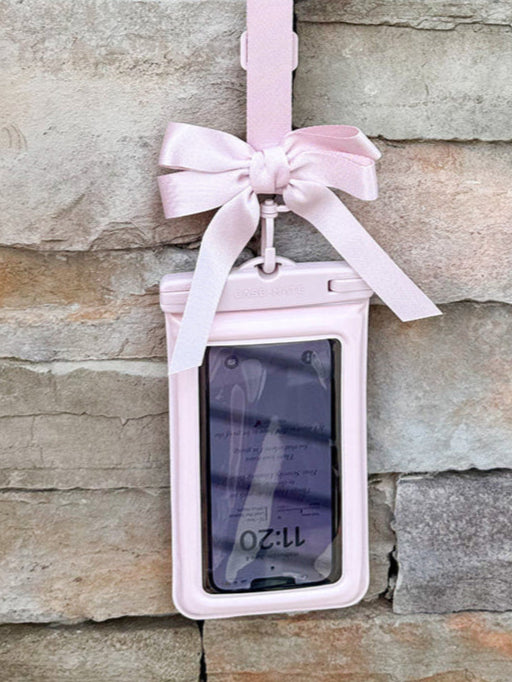 Pink waterproof phone pouch with a bow, floating design, and adjustable straps for beach or pool use.