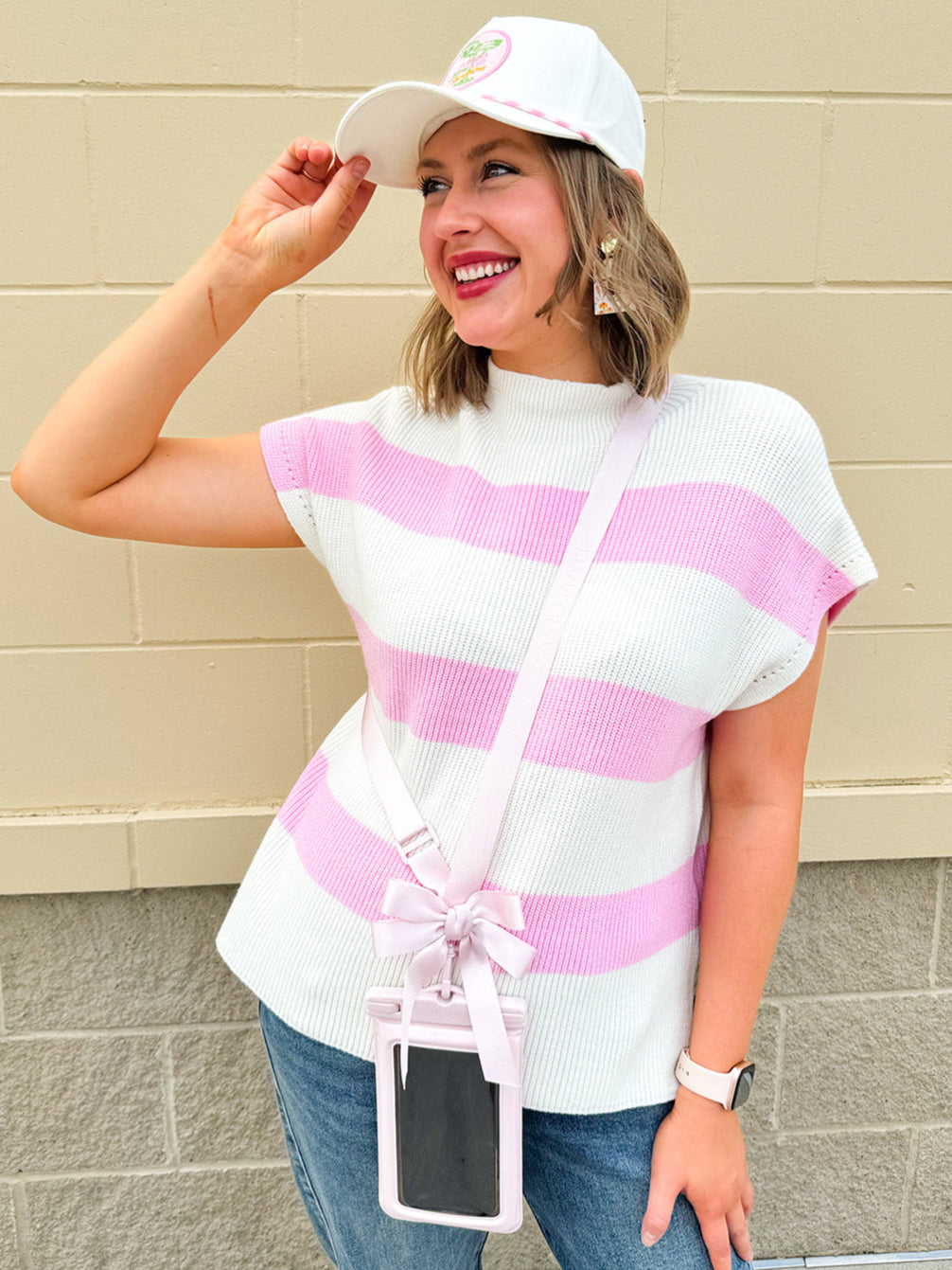 Pink waterproof phone pouch with a bow, floating design, and adjustable straps for beach or pool use.