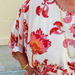 Cream midi dress with pink and orange floral print, scoop neckline, elastic waist, and flowy dolman sleeves.
