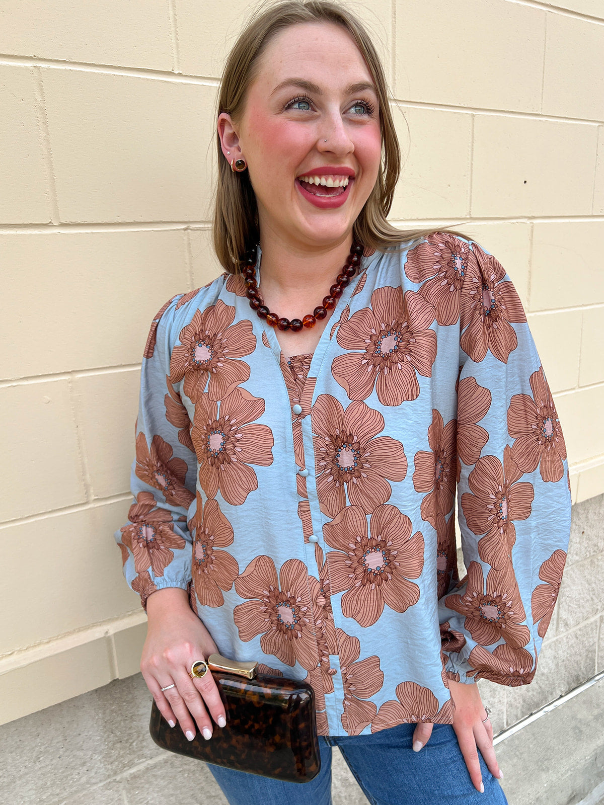 Blue long sleeve blouse with burnt orange floral details, slight ruffle sleeves, and front buttons