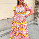 Blush pink and yellow floral print women’s midi dress with V-neckline, short puff sleeves, smocked elastic waist, and flowing skirt.