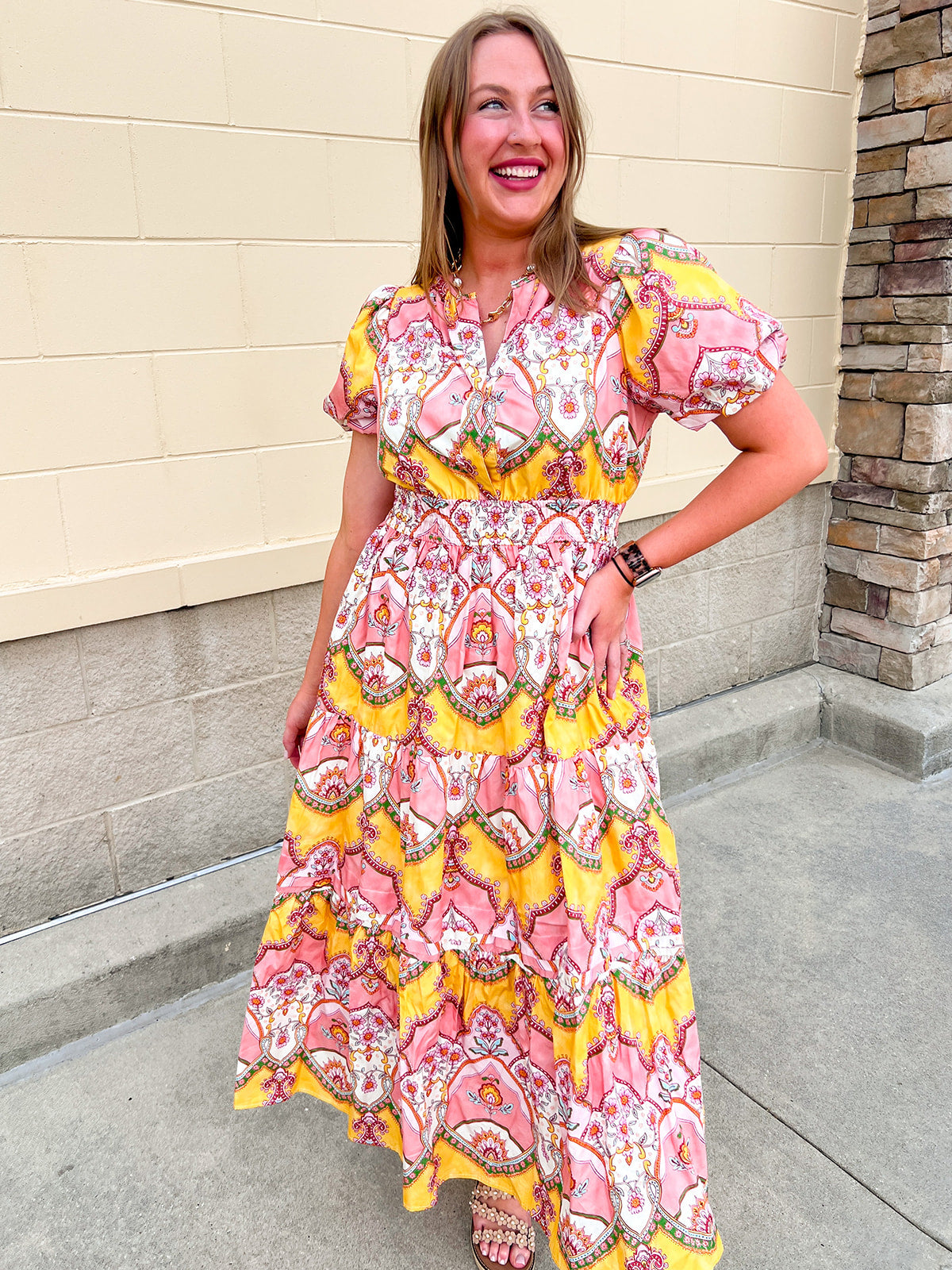 Blush pink and yellow floral print women’s midi dress with V-neckline, short puff sleeves, smocked elastic waist, and flowing skirt.