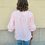 Blush blouse with V-neckline, balloon sleeves, front pleat, and ruffle-trimmed cuffs