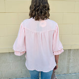 Blush blouse with V-neckline, balloon sleeves, front pleat, and ruffle-trimmed cuffs
