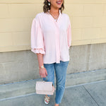 Blush blouse with V-neckline, balloon sleeves, front pleat, and ruffle-trimmed cuffs
