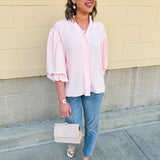 Blush blouse with V-neckline, balloon sleeves, front pleat, and ruffle-trimmed cuffs
