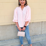 Blush blouse with V-neckline, balloon sleeves, front pleat, and ruffle-trimmed cuffs
