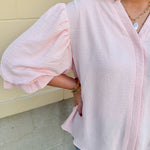 Blush blouse with V-neckline, balloon sleeves, front pleat, and ruffle-trimmed cuffs