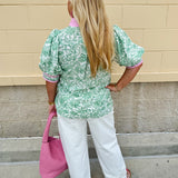 Green floral print caftan-style top with puff sleeves, split neckline, and lightweight fabric for effortless style.