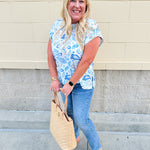 Blue paisley print cap sleeve blouse with round neckline and back button detail, styled for a soft and polished look.
