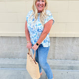 Blue paisley print cap sleeve blouse with round neckline and back button detail, styled for a soft and polished look.