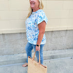 Blue paisley print cap sleeve blouse with round neckline and back button detail, styled for a soft and polished look.