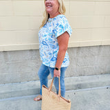 Blue paisley print cap sleeve blouse with round neckline and back button detail, styled for a soft and polished look.