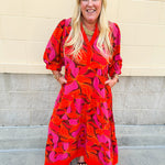 Pink, orange, and brown floral midi dress with v-neckline, tiered skirt, and ¾ puff sleeves.