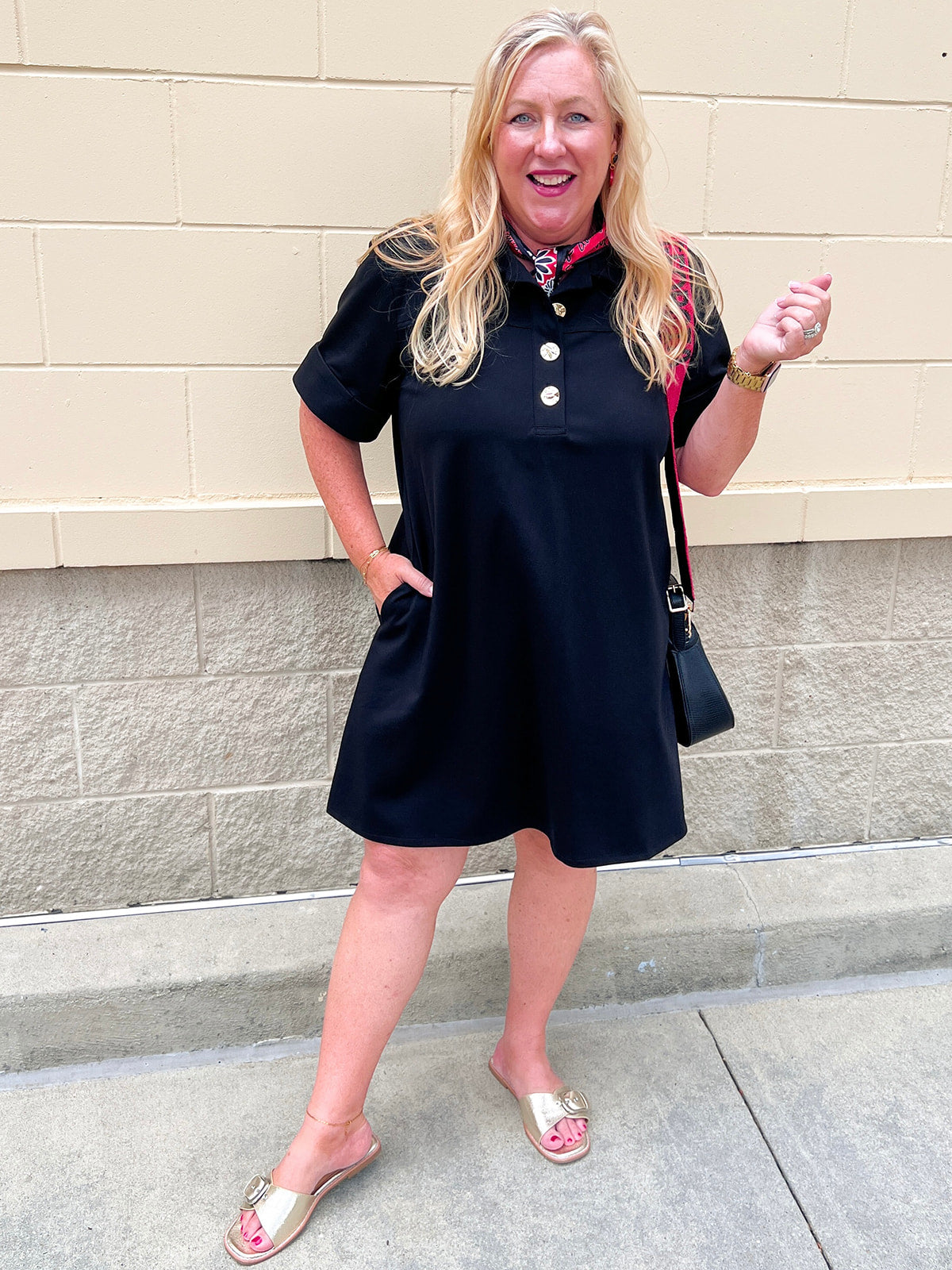 Black short sleeve A-line dress with collared neckline, three gold buttons, and knee-length silhouette.