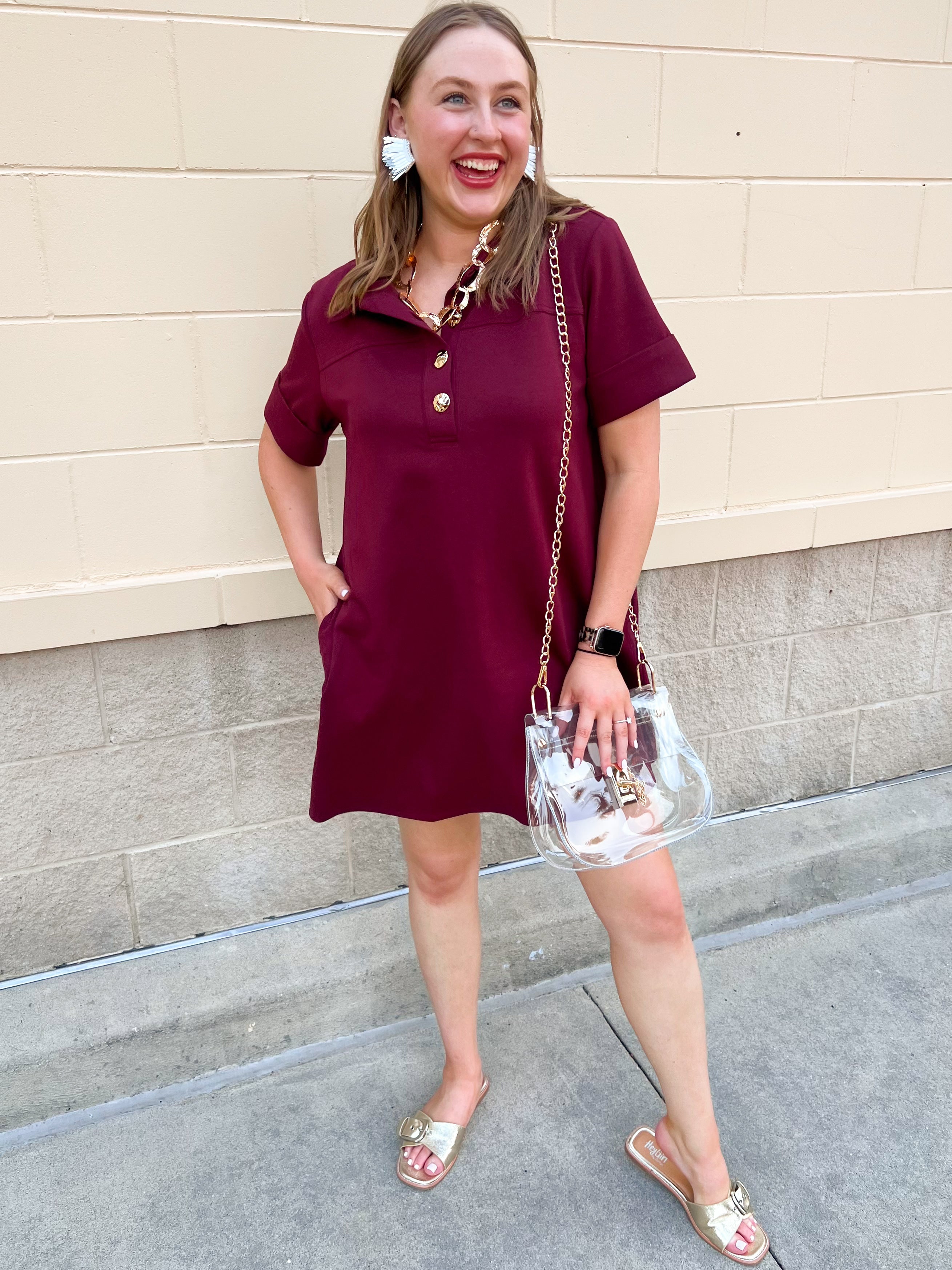 Garnet short sleeve A-line dress with collared neckline, three gold buttons, and knee-length silhouette.