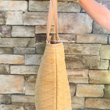 Natural oversized V-quilted straw tote with vegan leather trim, zipper closure, and multiple interior pockets