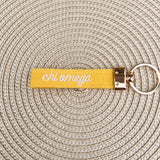 Double-sided embroidered Chi Omega sorority keychain featuring Greek letters, script sorority name, and polished gold hardware.