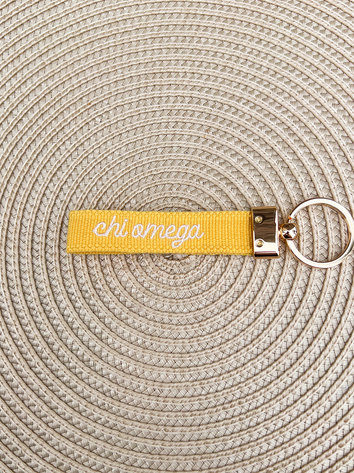 Double-sided embroidered Chi Omega sorority keychain featuring Greek letters, script sorority name, and polished gold hardware.