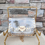 Clearly Handbags Jackie clear PVC crossbody bag with gold hexagon stud accents, gold chain strap, and structured silhouette.