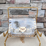 Clearly Handbags Jackie clear PVC crossbody bag with gold hexagon stud accents, gold chain strap, and structured silhouette.
