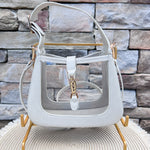 Clear stadium-approved handbag with ivory crocodile-textured vegan leather trim, gold hardware, top handle, and removable crossbody strap.
