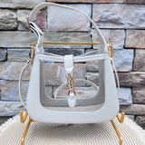 Clear stadium-approved handbag with ivory crocodile-textured vegan leather trim, gold hardware, top handle, and removable crossbody strap.