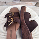 Chocolate brown faux suede wedge sandals with double straps and oversized gold buckles.