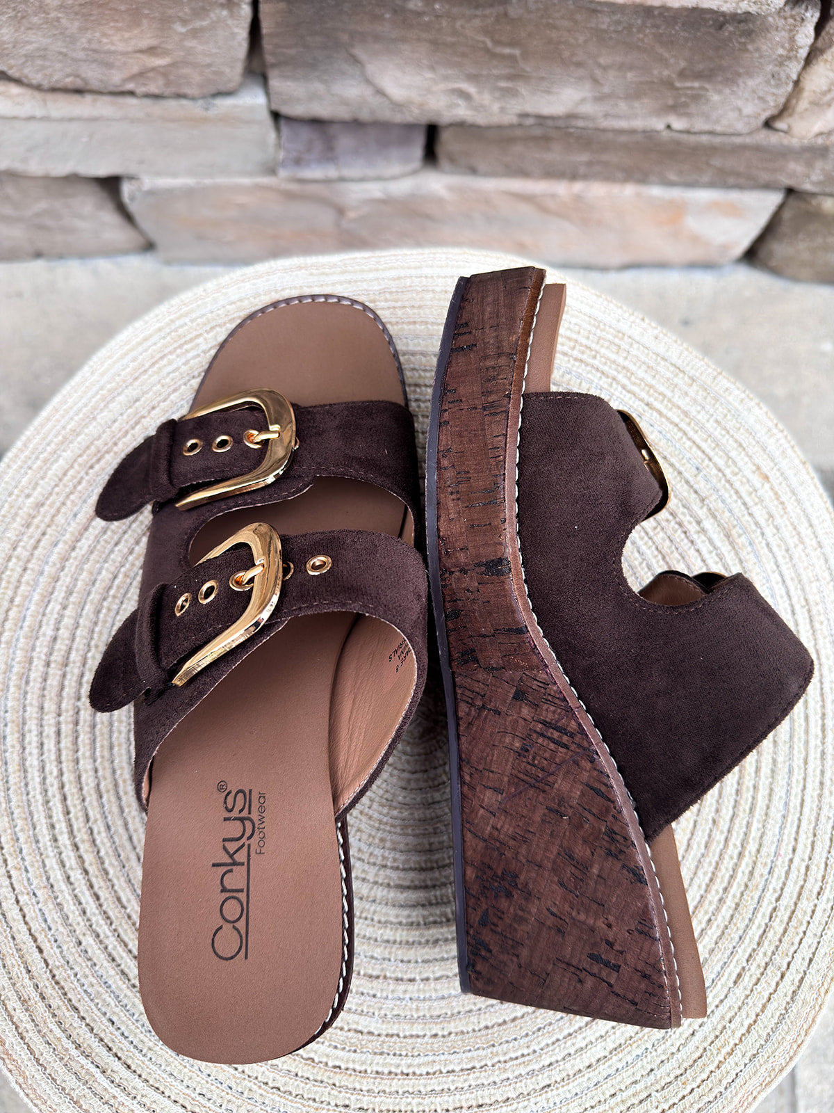 Chocolate brown faux suede wedge sandals with double straps and oversized gold buckles.