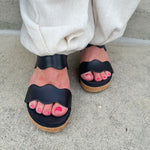 Black scalloped wedge sandals with cork sole, gold hardware accents, and dual straps—stylish and comfortable for everyday wear.
