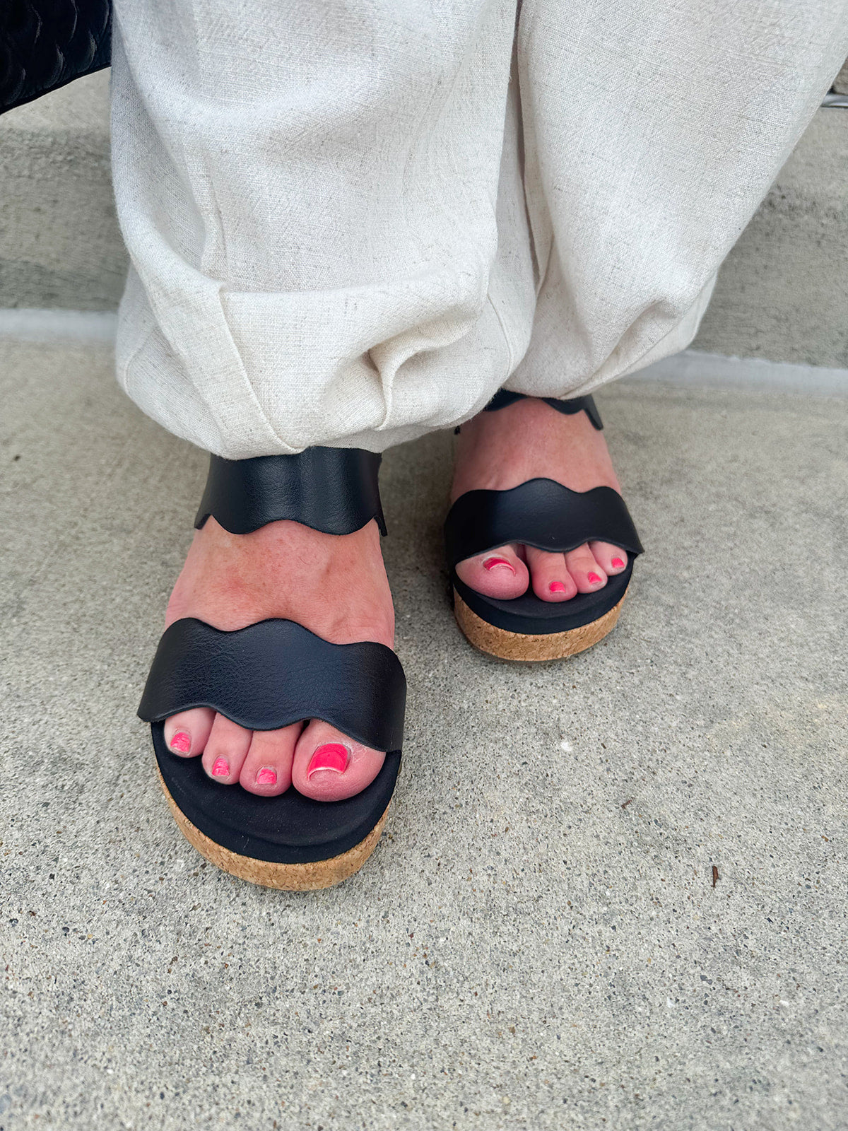 Black scalloped wedge sandals with cork sole, gold hardware accents, and dual straps—stylish and comfortable for everyday wear.