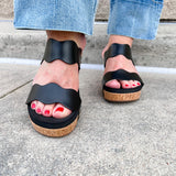 Black scalloped wedge sandals with cork sole, gold hardware accents, and dual straps—stylish and comfortable for everyday wear.
