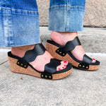 Black scalloped wedge sandals with cork sole, gold hardware accents, and dual straps—stylish and comfortable for everyday wear.