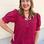Garnet embroidered blouse with applique accents, puff sleeves, ruffle band collar, and button-front closure.