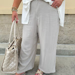 Wide-leg linen pants in a stone color with high-rise waist and pockets, styled for casual elegance.