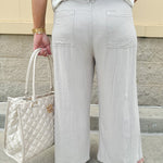 Wide-leg linen pants in a stone color with high-rise waist and pockets, styled for casual elegance.