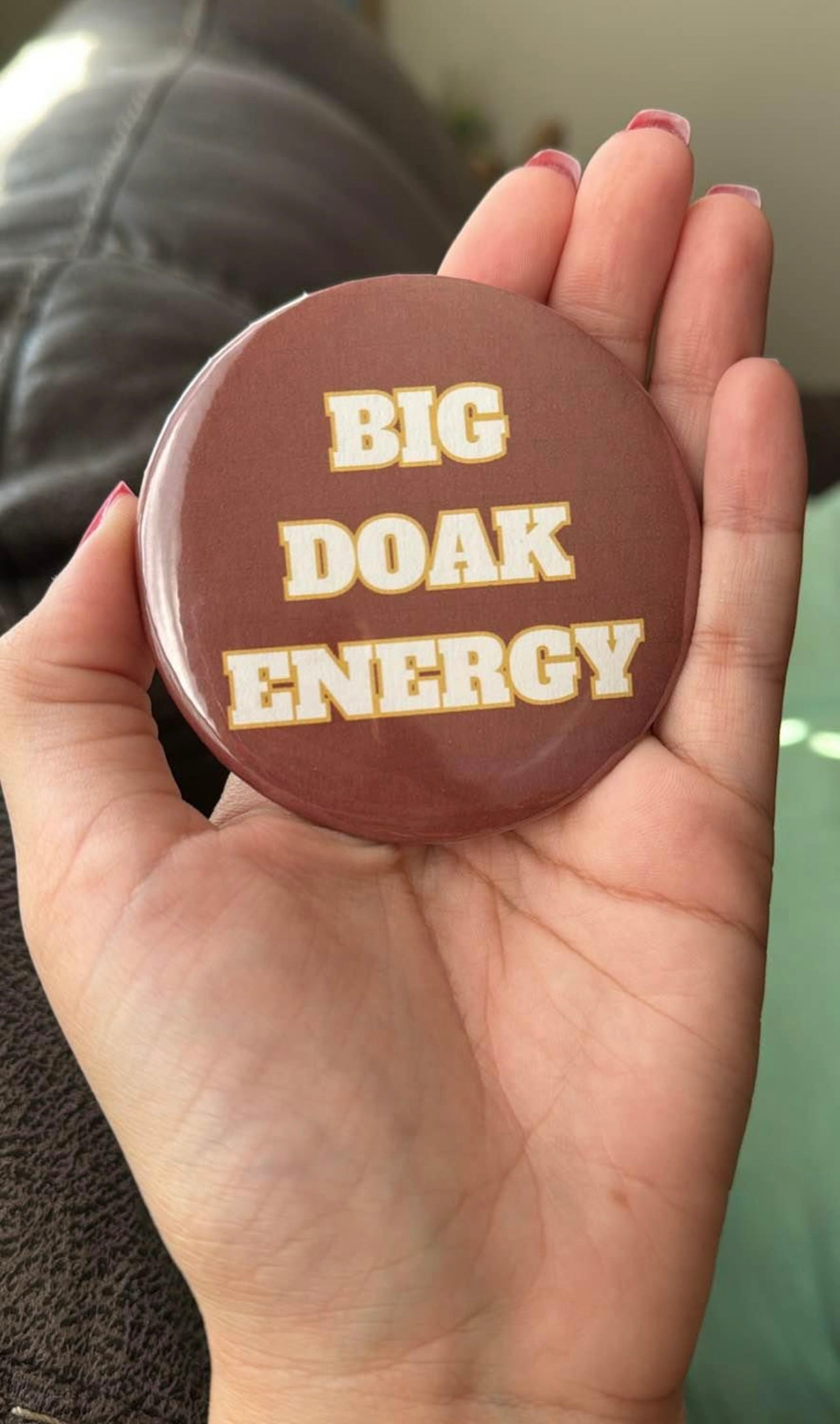 Round button in garnet with white and gold lettering that reads “Big Doak Energy.”
