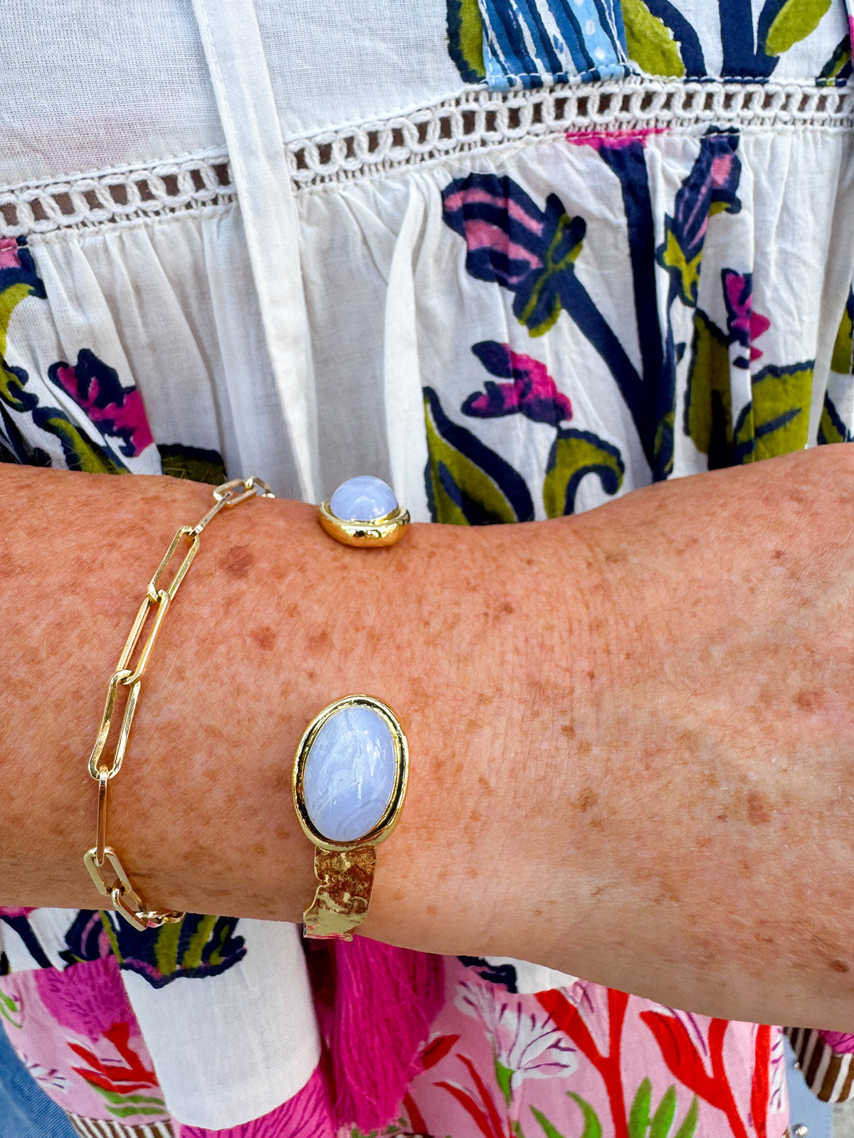 Gold cuff bracelet with an oval blue lace agate stone at the center, offering soft blue tones and a serene, elegant feel.