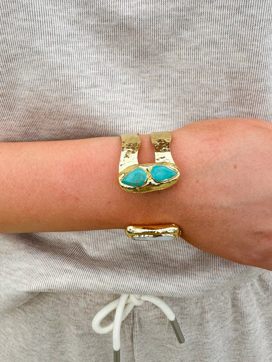 Gold double cuff bracelet featuring a mother of pearl on one end and a turquoise stone on the other—elegant, stylish, and stackable.