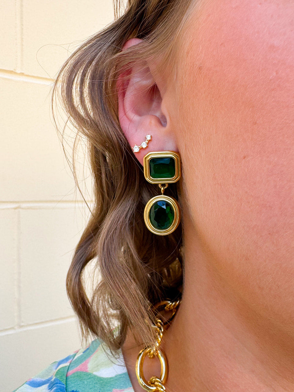 Dangle earrings with emerald green rectangular stud and matching circular gem drop, set in gold for a classic and elegant finish.