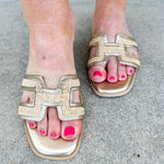 Ena Raffia H-Cutout Slides featuring a breathable raffia strap and modern H-cutout design, styled on a clean surface to showcase their chic, casual summer look and cushioned footbed